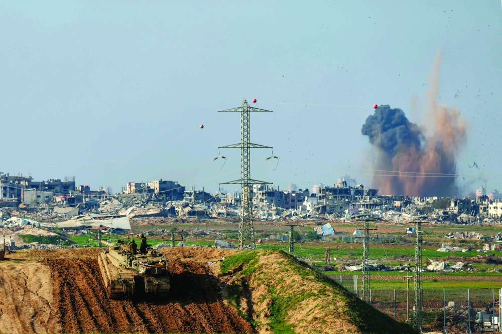 This picture shows smoke billowing over the Palestinian territory during Israeli bombardment as an Israeli tank takes position. — AFP