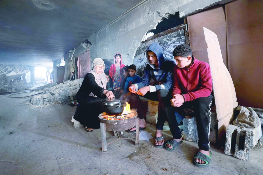 Displaced Palestinians prepare food as they take shelter inside a building damaged during Israeli bombardment in Rafah. — AFP