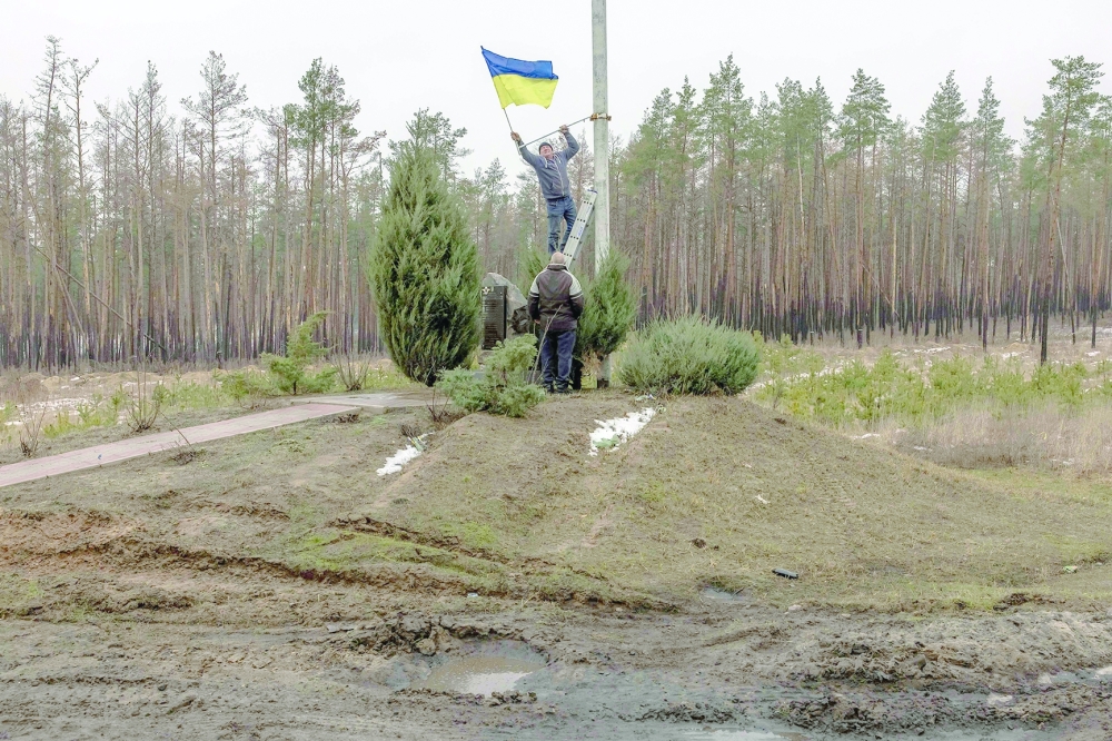 A man installs a Ukrainian flag on a memorial for Ukrainian soldiers in Kramatorsk district. — AFP 