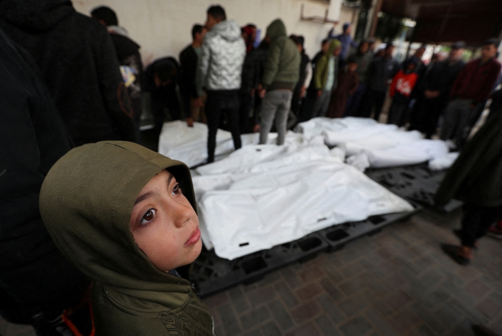 A child looks on as mourners react next to the dead bodies including four Palestinians killed in an Israeli strike