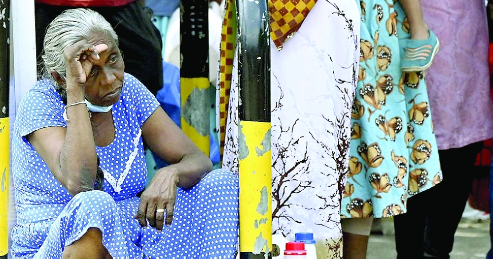 A woman waits in a queue to buy kerosene for home use at a service station in Colombo. - AFP file photo