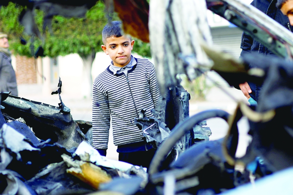 A Palestinian boy inspects the remains of a car in the aftermath of an Israeli strike, in Rafah in the southern Gaza Strip. — Reuters 