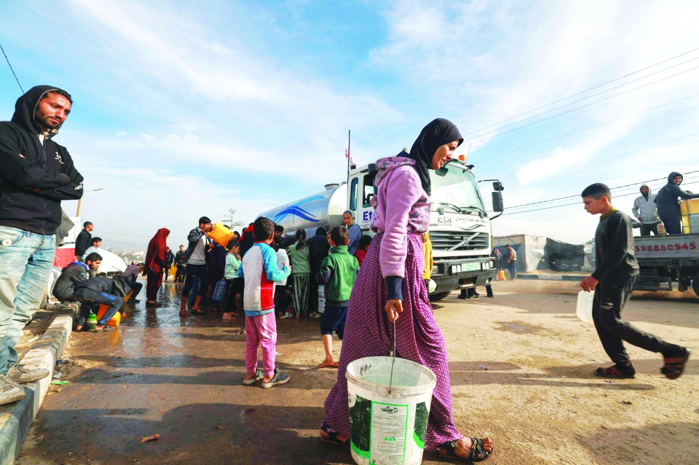Displaced Palestinians queue to replenish their water supply from a truck provided by the Doctors Without Borders NGO in a makeshift tent camp in Rafah. — AFP