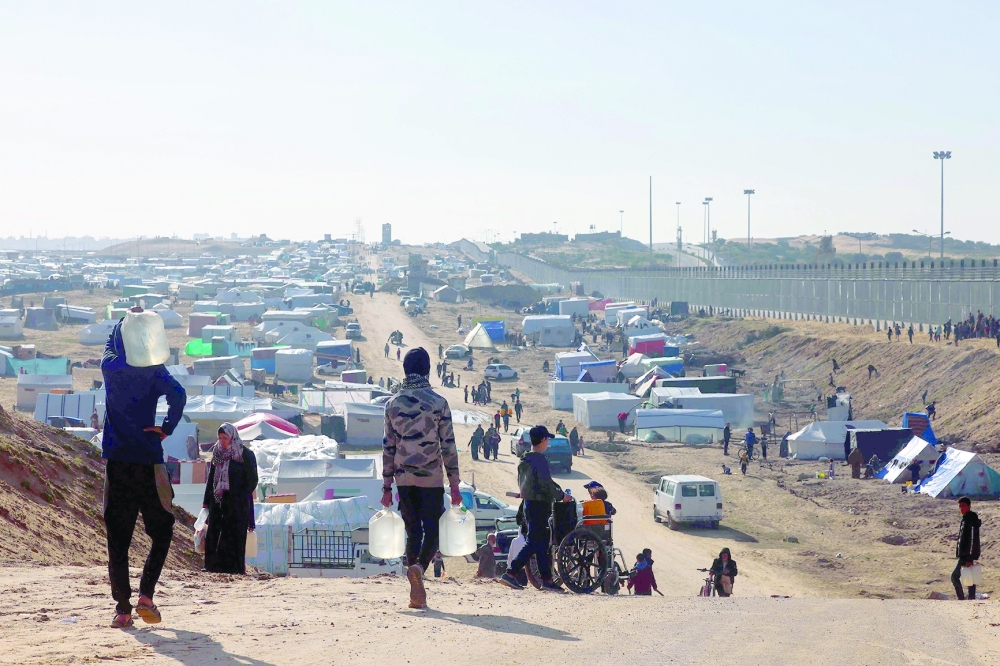 People ferry water at a makeshift tent camp for displaced Palestinians in Rafah near the border with Egypt in the southern Gaza Strip. - AFP

