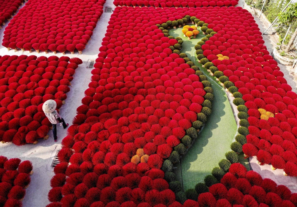 A worker walks past incense sticks arranged in the form of a Vietnamese map in a courtyard in the village of Quang Phu Cau on the outskirts of Hanoi. - AFP