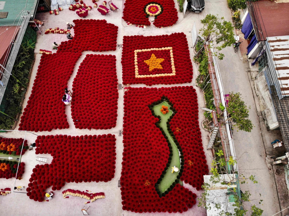 Tourists pose in front of incense sticks arranged in the form of a Vietnamese map map and flag in a courtyard in the village of Quang Phu Cau on the outskirts of Hanoi. - AFP 