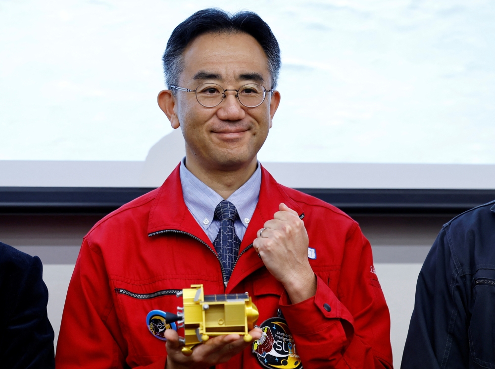 Shinichiro Sakai, project manager, Smart Lander for Investigating Moon (SLIM) project team poses with a miniature model of SLIM after a press conference in Tokyo. - Reuters
