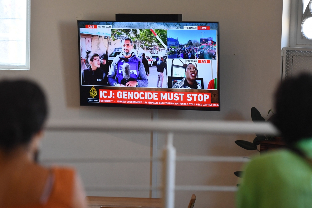 People gather to watch the International Court of Justice (ICJ) ruling of the case against Israel brought by South Africa in The Hague 