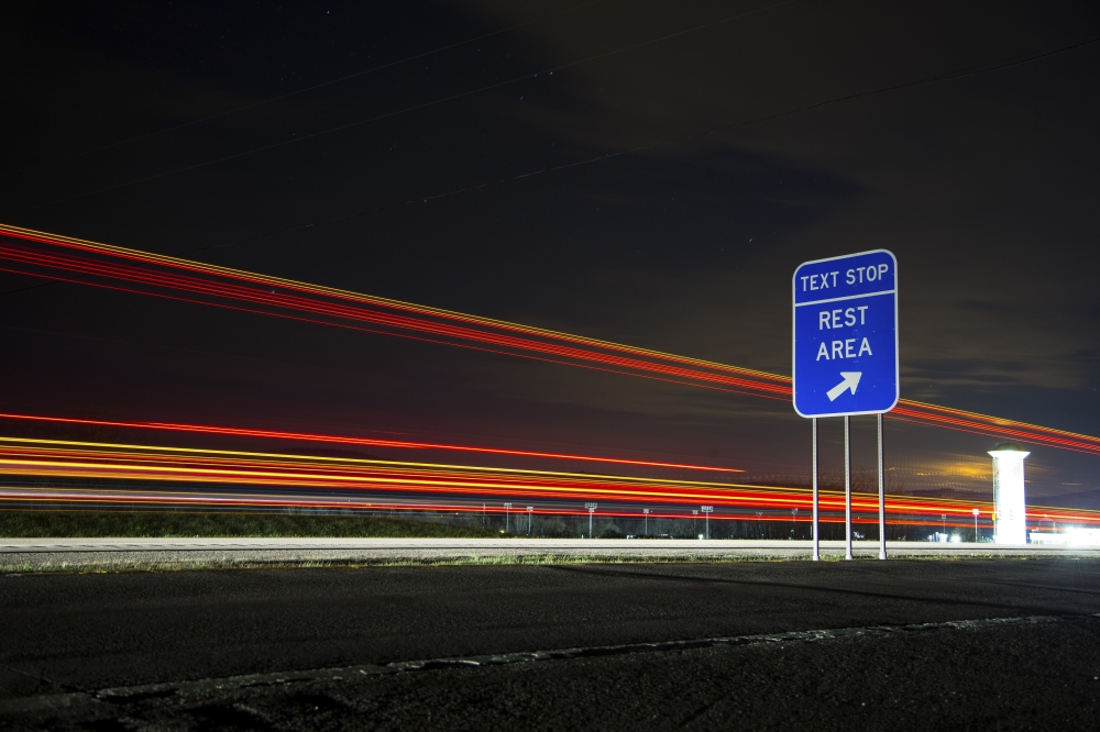 A highway sign encourages drivers to stop at a rest area for safe texting