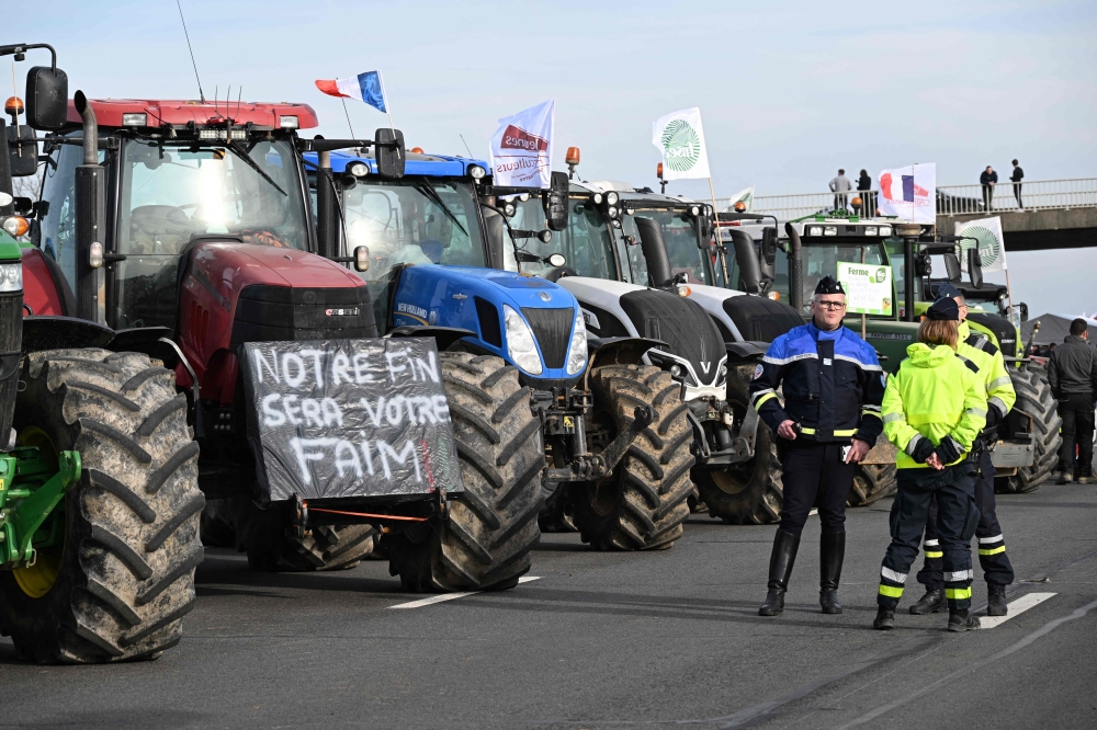 French police stand next to tractors as farmers take part in a road block protest on the A4 highway near Jossigny, east of Paris. — AFP 