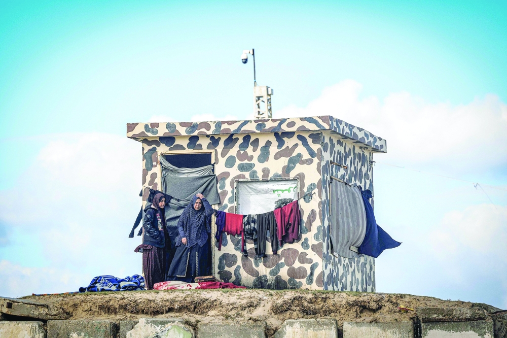 Women stand by outside a Palestinian outpost where they are taking refuge near a make-shift shelter for Palestinians who fled to Rafah. — AFP