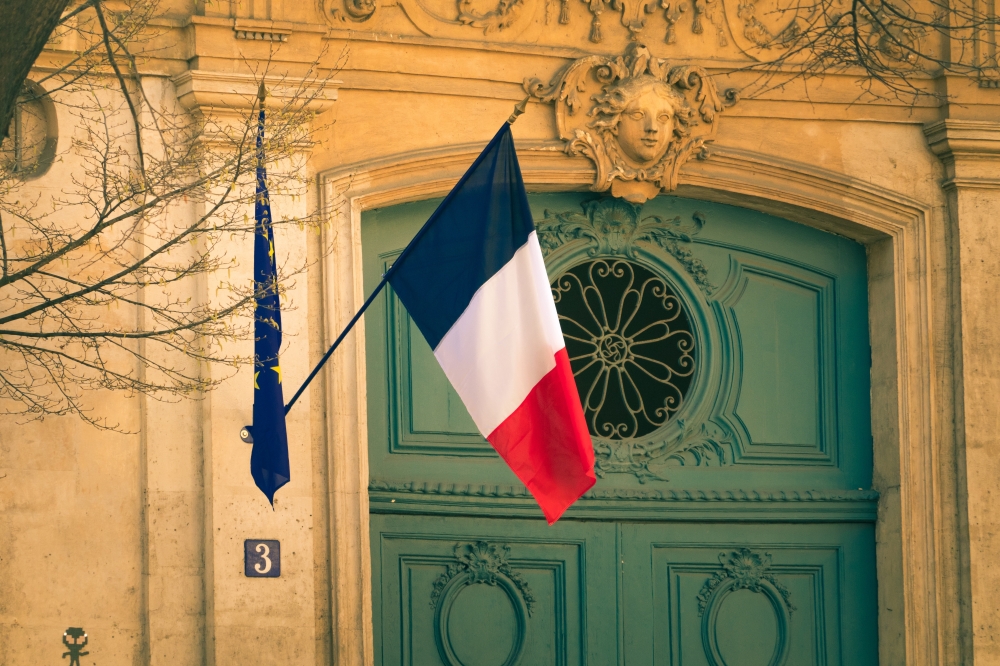 french flag hanging outside a beautifully ornate.