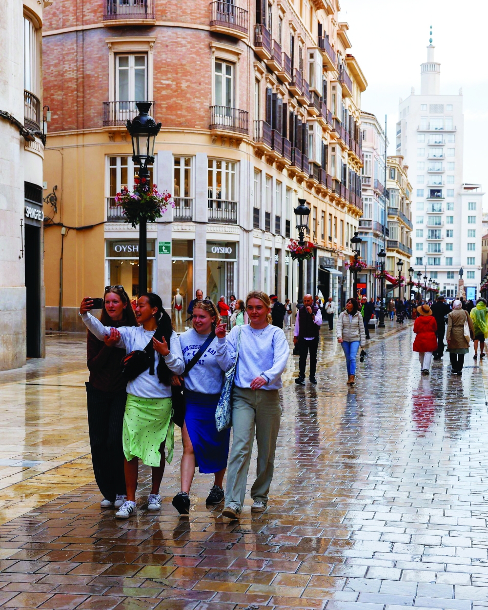 Tourists walk along a shopping street in central Malaga, Spain. — Reuters
