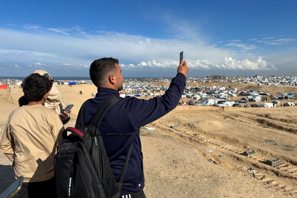 Displaced Palestinians hold up their mobile device as they try to get internet signal to communicate with their relatives in Rafah in the southern Gaza Strip. - Reuters