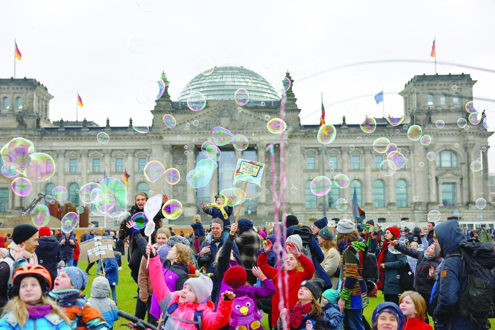 Children play with soap bubbles as people gather outside the Reichstag building to protest against right-wing extremism, in Berlin. — Reuters 