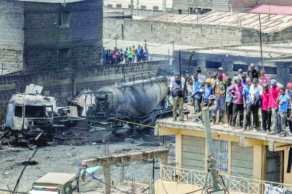 People stand on top of damaged buildings to see the wreckage of burnt trunks and tankers after a gas explosion in the Embakasi area of Nairobi on Feb. 2. — AFP 