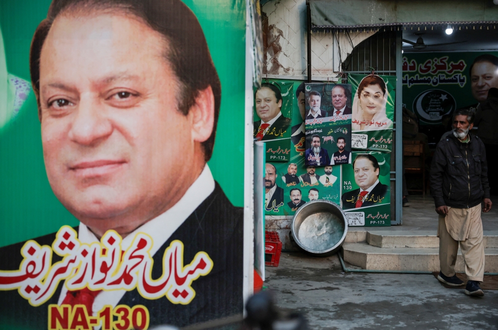 A man stands near the banner and campaign posters of Pakistan Muslim League-Nawaz (PML-N)