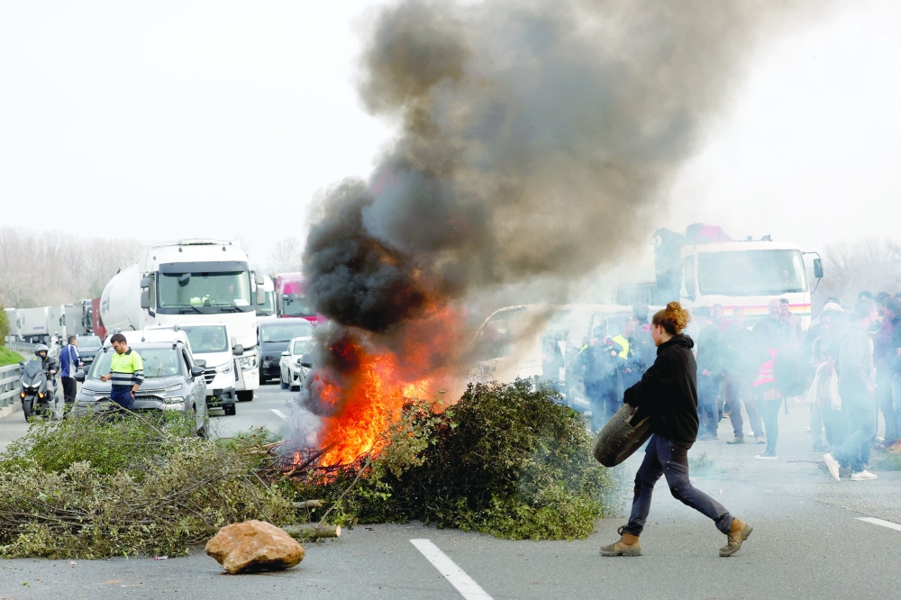 Tree branches are set on fire on an AP-7 highway as farmers protest across Europe, near Girona, Spain. — Reuters