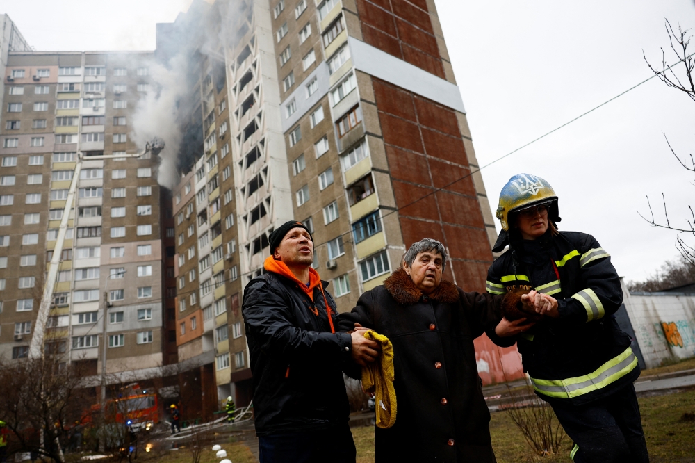 Firefighters help a woman from a building damaged during a Russian missile strike, amid Russia's attack on Ukraine, in Kyiv. — Reuters 