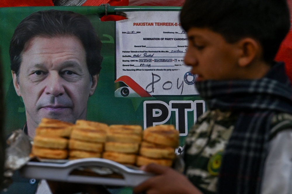A child walks past a poster showing portrait of jailed Pakistan痴 former prime minister Imran Khan