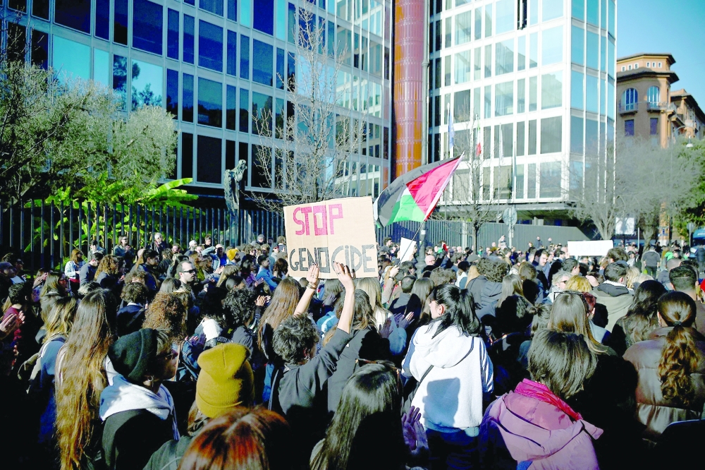 Demonstrators, one holding a placard and another the Palestinian flag during a 'Protest for Palestine' and in front of Italian national television headquarter RAI, in central Romeon. — AFP