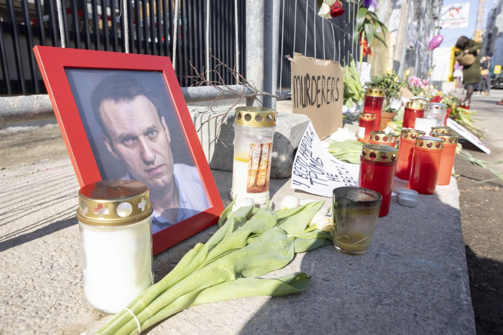 A picture of late Kremlin's critic Alexei Navalny lays next to flowers and candles at a makeshift memorial in front of the Russian embassy in Vienna. - AFP



