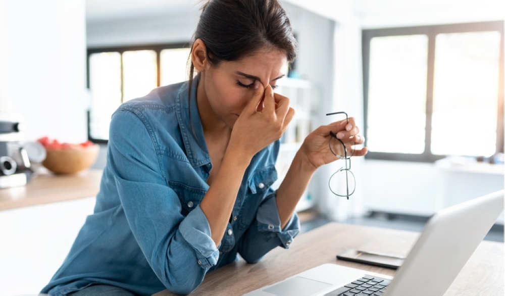 Stressed business woman working from home on laptop looking worried, tired and overwhelmed.