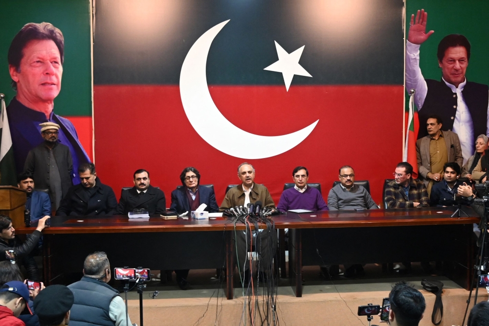 Former prime minister Imran Khan's Pakistan Tehreek-e-Insaf (PTI) party nominee for prime minister, Omar Ayub Khan (C) speaks during a press conference 