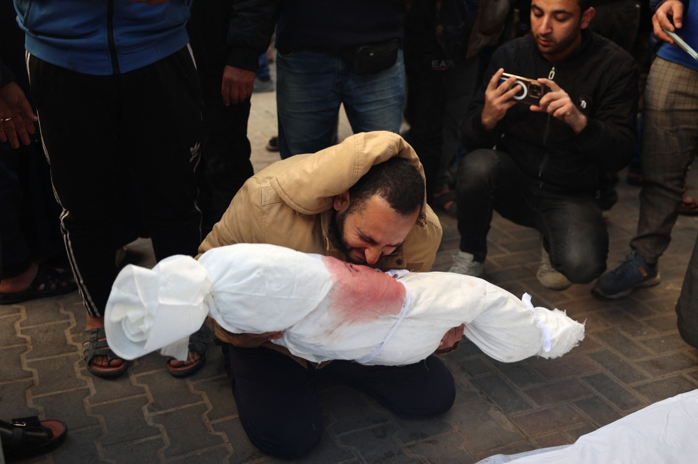  Palestinian man mourns as he holds the body of a child at Rafah's Al-Najjar hospital on February 21