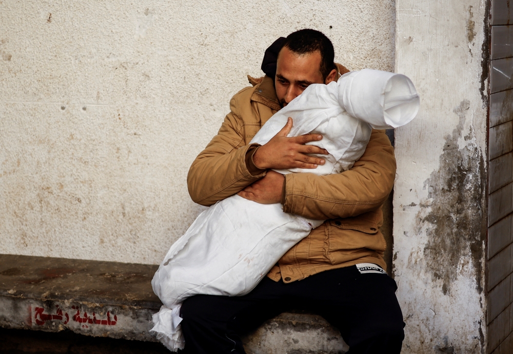 A Palestinian man reacts while carrying the body of his daughter who was killed in an Israeli strike, amid the ongoing conflict between Israel and Hamas, at Abu Yousef Al-Najjar hospital, in Rafah, in the southern Gaza Strip, February 21