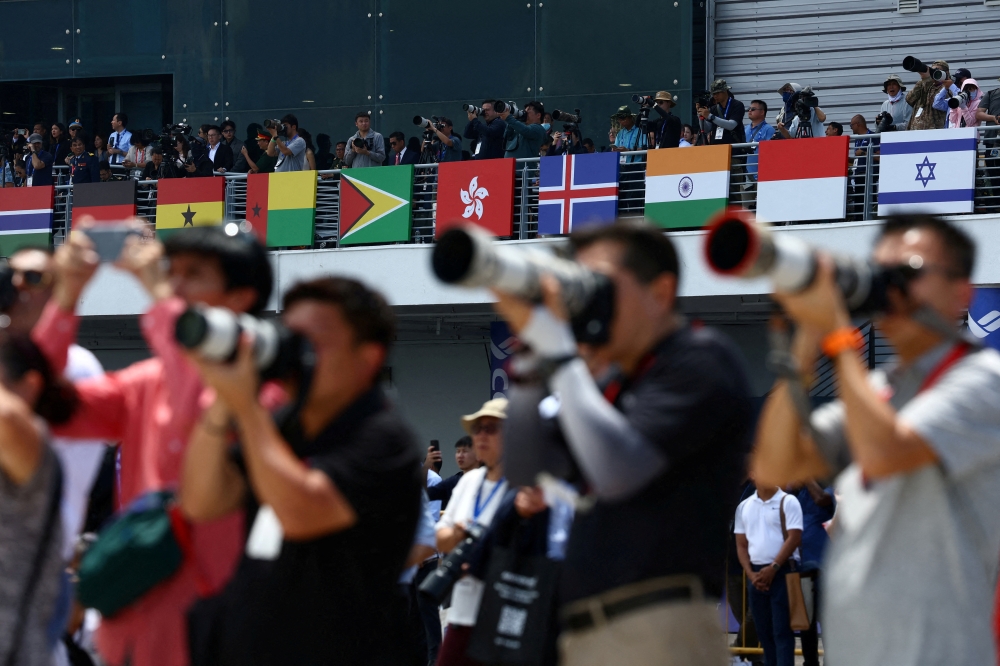 People take photos during an aerial display at the Singapore Airshow at Changi Exhibition Centre in Singapore. - Reuters 