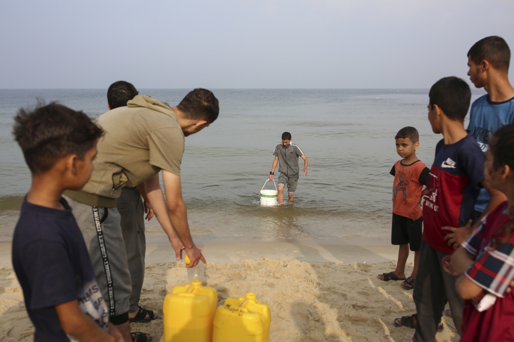 Displaced Palestinians fill jerrycans with seawater for washing and cooking, at the beach in Deir al-Balah, in the central Gaza Strip, Oct. 28, 2023.