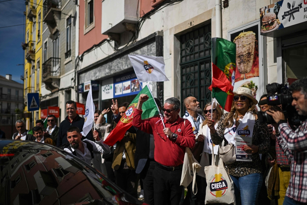 CHEGA party supporters hold flags during a rally in Graca neighbourhood, Lisbon. — AFP
