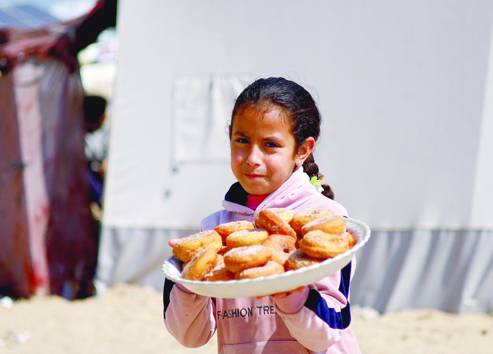 A child holds food in Rafah in the southern Gaza Strip on Monday. - Reuters