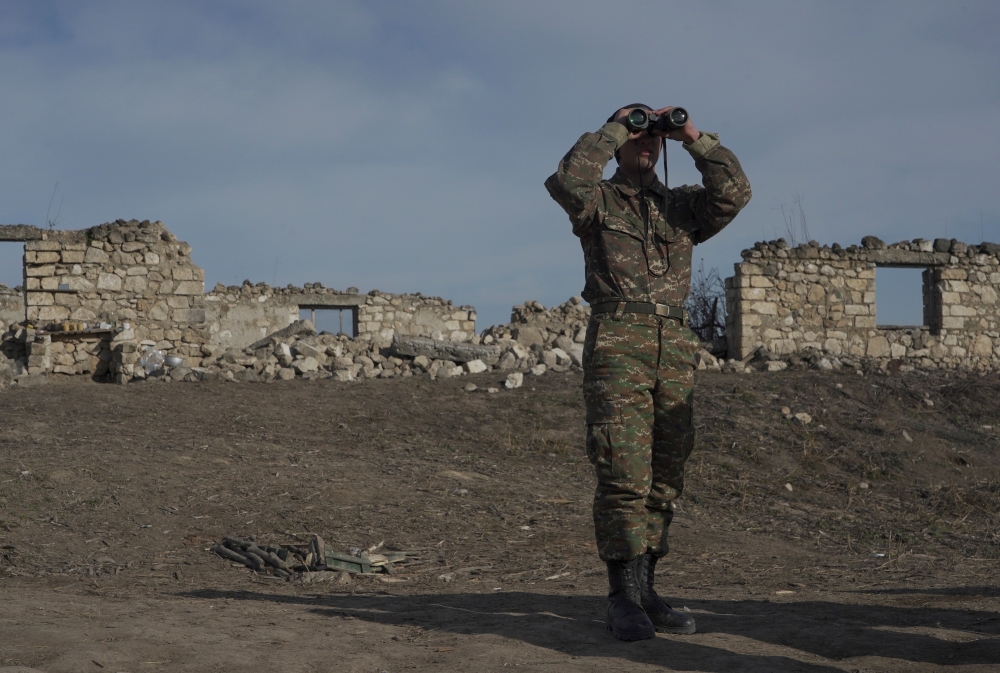 An Armenian soldier looks through binoculars as he stands at fighting positions near divided Taghavard village in Nagorno-Karabakh region. — Reuters file photo