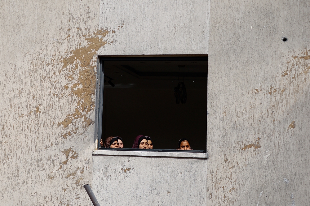 Palestinians look on at the site of an Israeli strike on a house, in Rafah. — Reuters 
