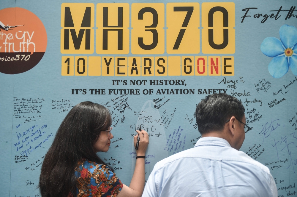 A woman writes a message during an event held by relatives of the passengers and supporters to mark the 10th year since the Malaysia Airlines flight MH370 carrying 239 people disappeared from radar screens 