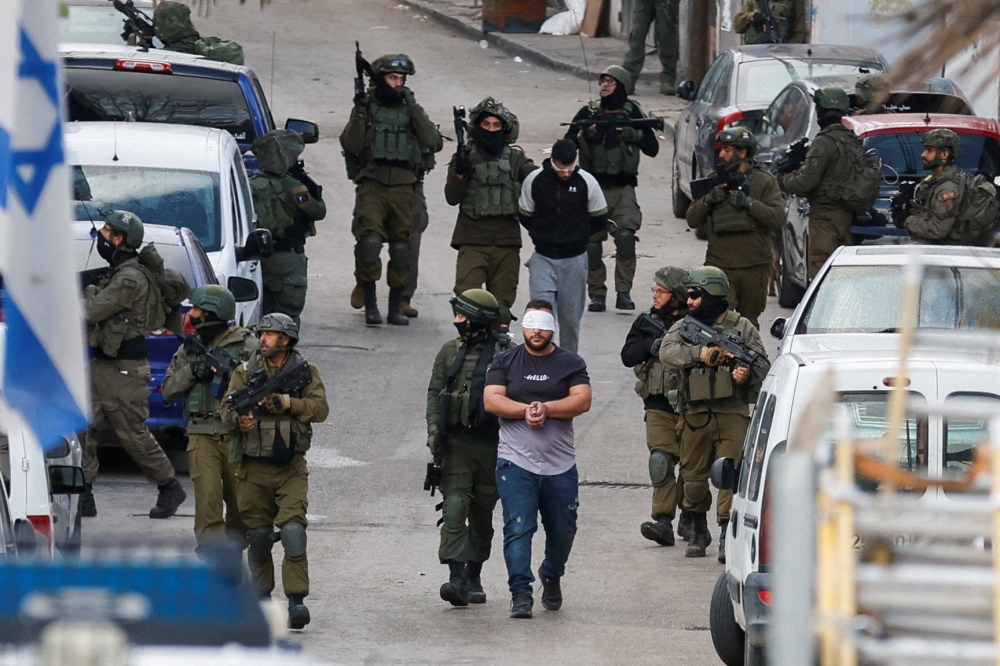 Israeli soldiers detain Palestinians during a raid, in Ramallah. — Reuters 