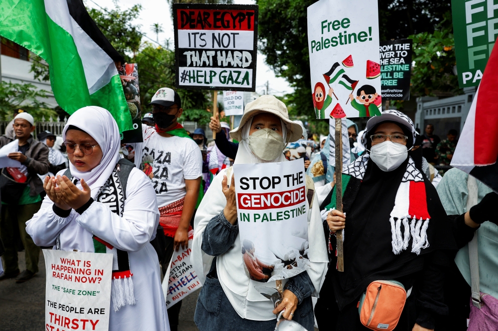 Demonstrators holding placards take part during a protest urging to open the Rafah border, in Jakarta, Indonesia. — Reuters 