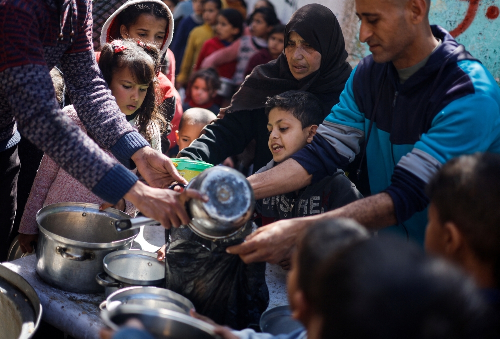Palestinian children wait to receive food cooked by a charity kitchen amid shortages of supplies, in Rafah. — Reuters 