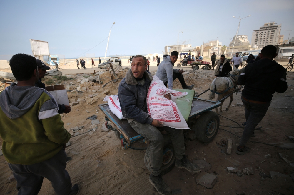 Palestinians transport bags of flour as humanitarian aid arrives in Gaza City on Wednesday. — AFP