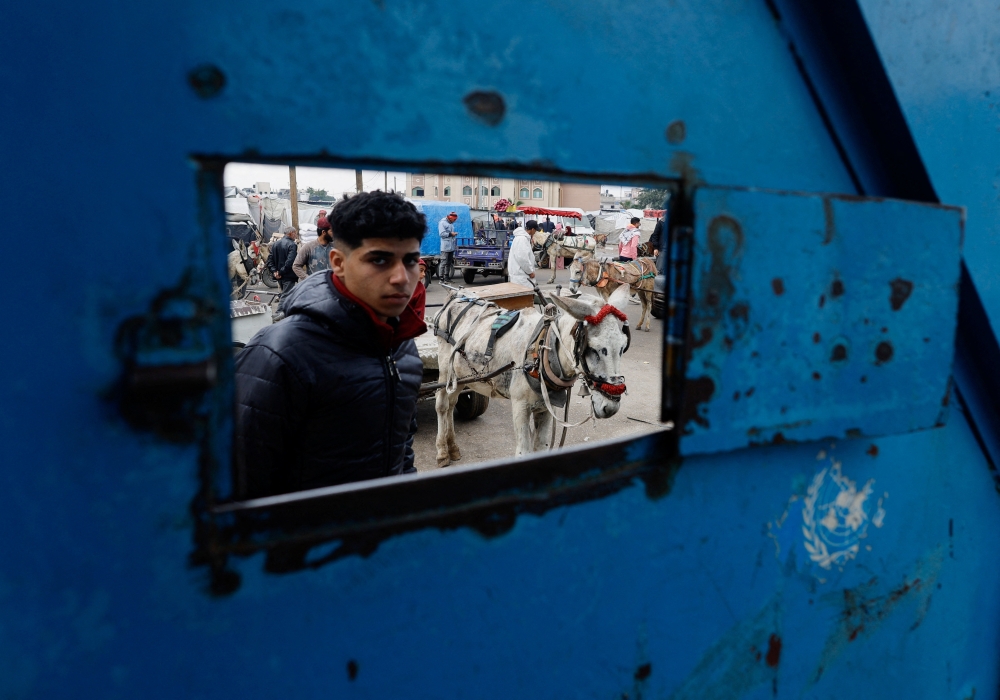 Displaced Palestinians wait to receive United Nations Relief and Works Agency (UNRWA) aid, in Rafah