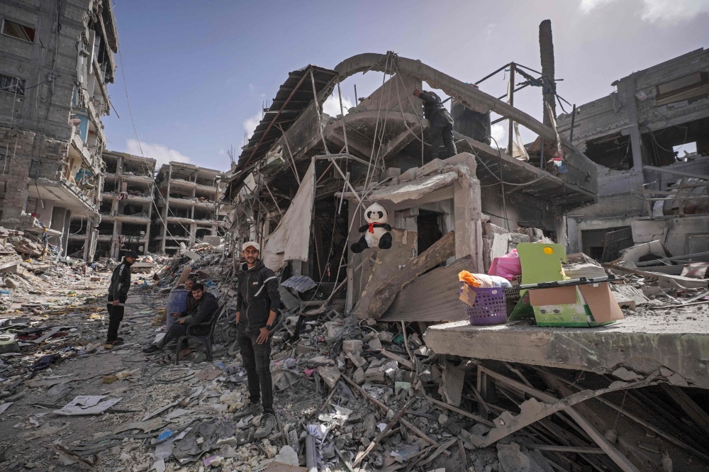 Palestinians stand amid the rubble of houses destroyed by Israeli bombardment in Khan Yunis in the southern Gaza Strip on Wednesday. — AFP
