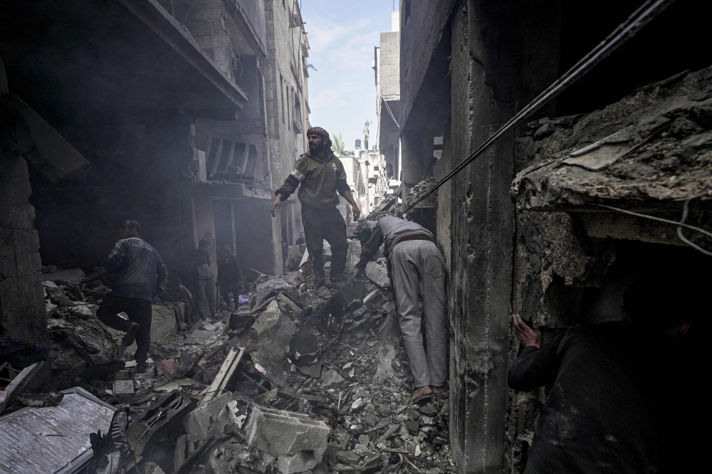Palestinians inspect the rubble of a building in Deir el-Balah following Israeli bombardment, in the central Gaza Strip