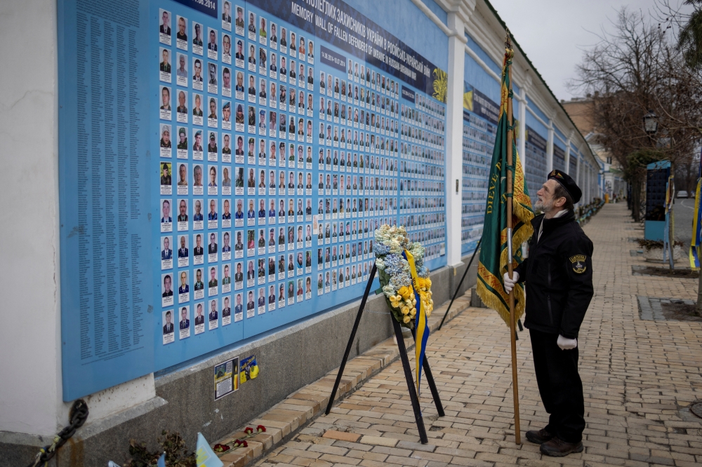 A member of a Lithuanian military delegation looks at a memorial wall of servicemen who lost their lives during war with Russia outside St. Michael's Golden-Domed Cathedral in Kyiv