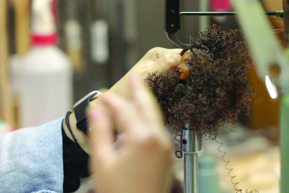 Shirley Fujisaki, Key Lead Hair Designer, inserts fiber hair onto the head of a Barbie doll at Mattel Design Center in El Segundo, California, U.S., February 22, 2024.