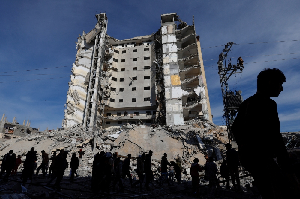 Palestinians gather near a building damaged in an Israeli air strike, in Rafah. — Reuters 
