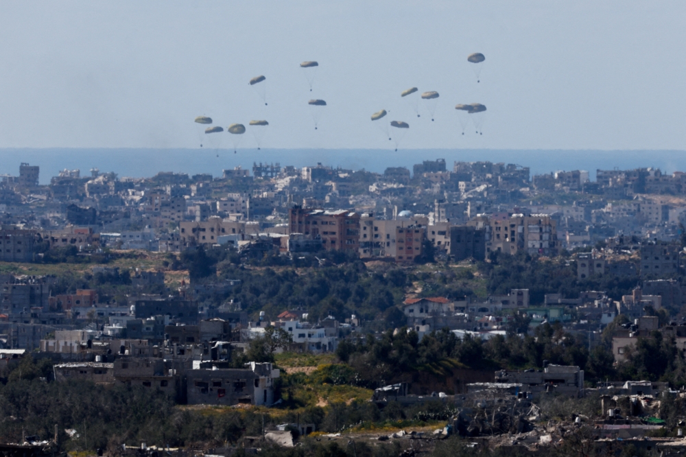 Packages fall towards northern Gaza, after being dropped from a military aircraft, as seen from Israel's border. — Reuters 