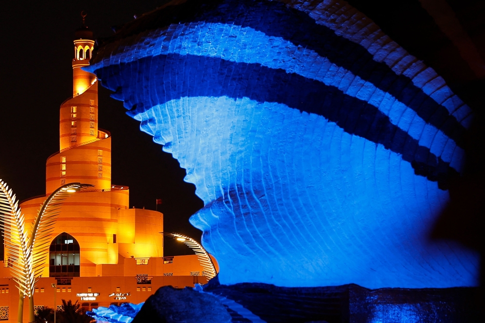 The Al Fanar, Qatar Islamic Cultural Center, stands behind a fountain lit in blue on the second day of Islam's holy fasting month of Ramadan in Doha on March 12, 2024.  (Photo by KARIM JAAFAR / AFP)

