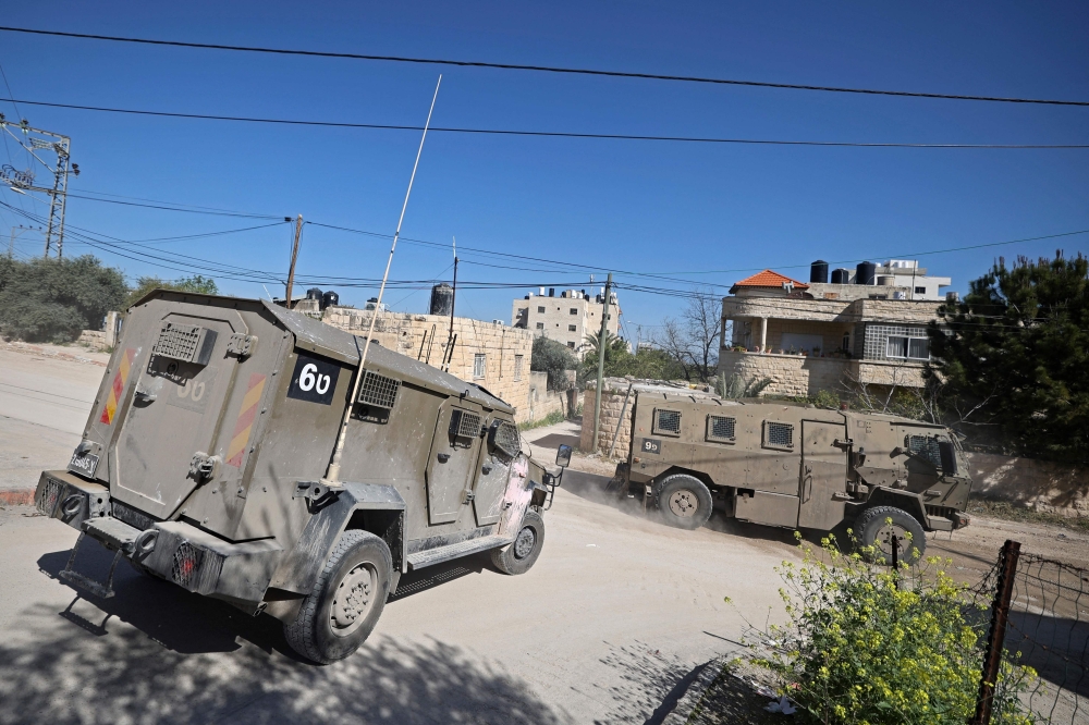 Israeli military vehicles patrol along a street during a raid at the Jenin refugee camp in the West Bank. — AFP 